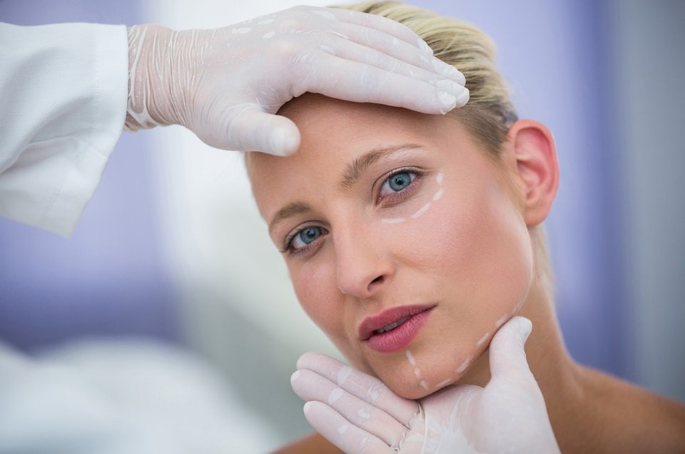 Close-up of doctor examining female patients face for cosmetic treatment